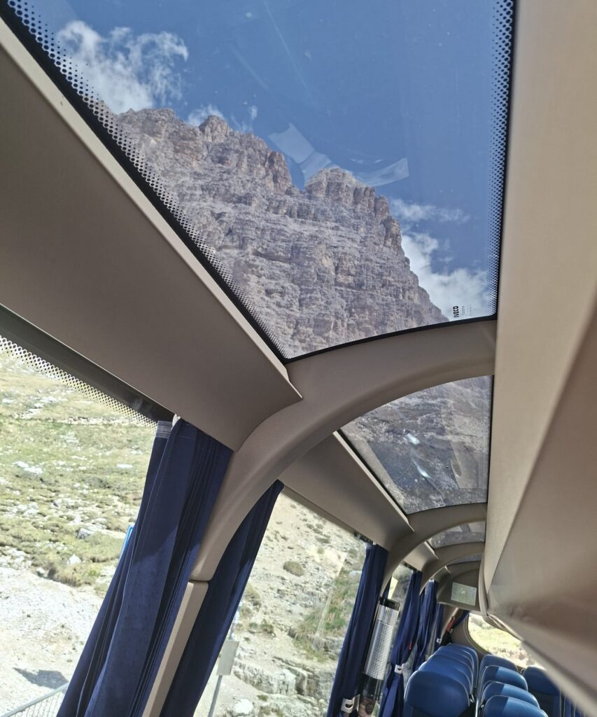 Výhľad cez panoramatickú strechu Open Sky na hory z autobusu Hanke